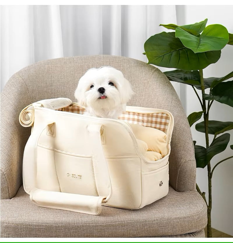 bichon-maltais-avec-la-tete-qui-sort-d'un-sac-de-transport-pour-chien-beige-posé-sur-un-fauteuil
